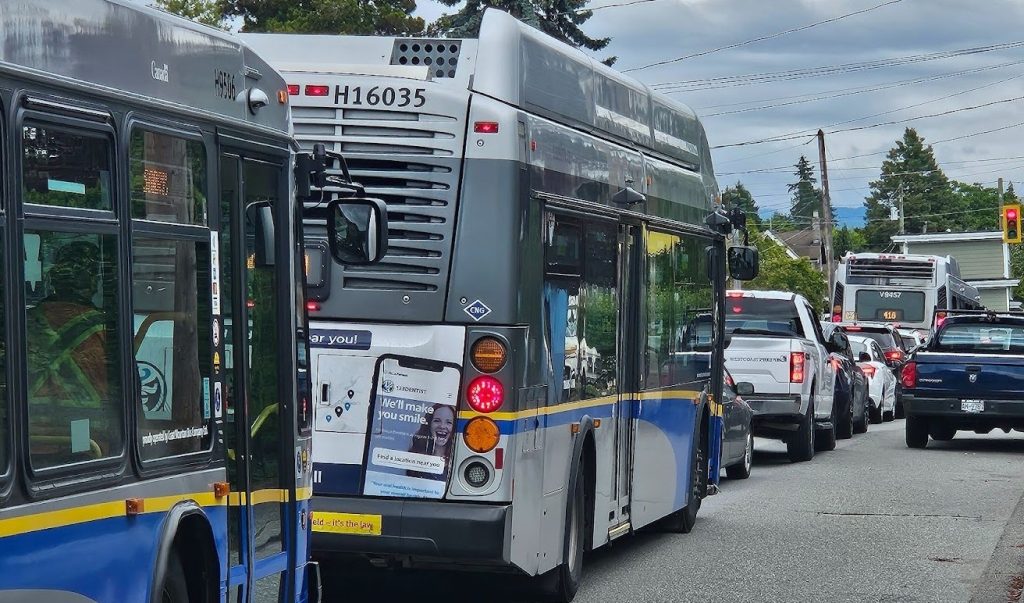 A queue of buses leaving 22nd St SkyTrain station in New West on 7th Avenue.