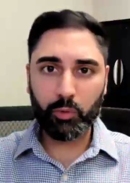 man with beard and button uup shirt talking to camera