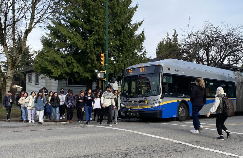 Crowds of transit riders in front of the bus. The soon to be relieved route 49.
